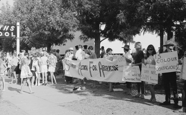 safa protest group with banners and placards outside a country swimming pool