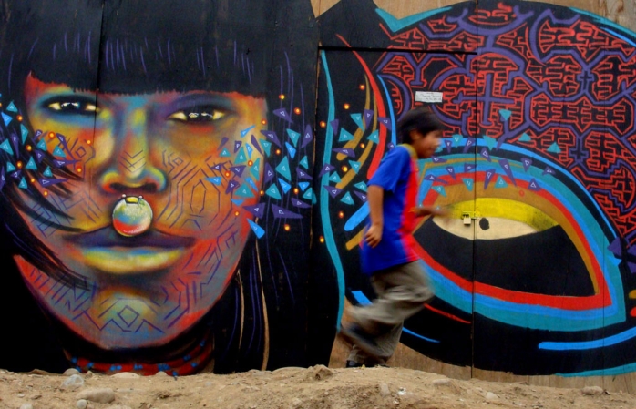 a young boy runs past one of lima\'s many graffiti murals.