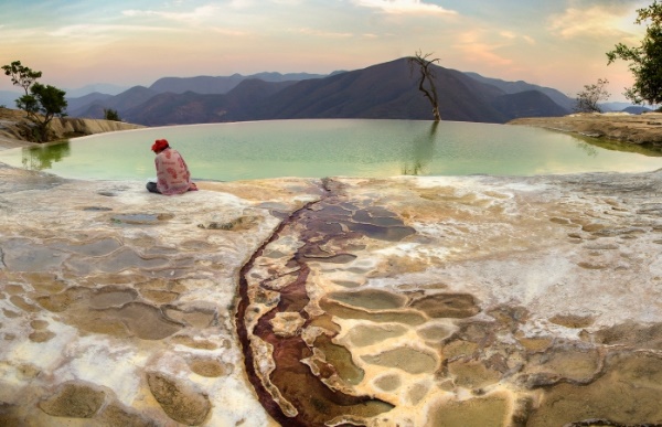 a woman reads atop of the water rock formations and pools of oaxaca.